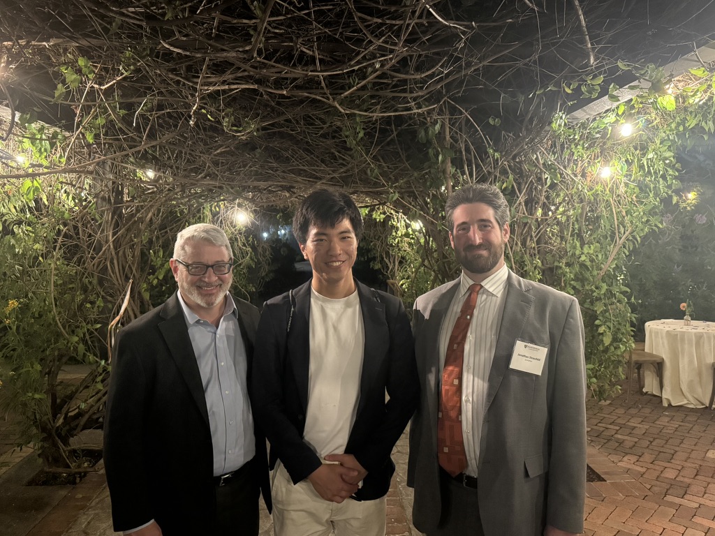Chinat standing between the two authors of Johns Hopkins: The First 150 Years under a canopy of vines at the sesquicentennial reception in San Francisco.